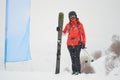 Freerider woman skier with fat/wide all mountain skis posing next to a blank blue flag, during a whiteout day in Les Sybelles.