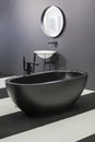 Freestanding black bathtub, stylish minimalist black and white loft style bathroom. Bath, washstand, mirror on the wall