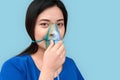 Freestyle. Chinese woman in oxygen mask standing isolated on grey breathing relaxed close-up