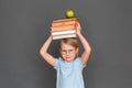 Freestyle. Little girl in eyeglasses isolated on grey with books and apple above the head smiling joyful Royalty Free Stock Photo