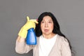 Freestyle. Mature lady in rubber gloves standing isolated on grey with spray near head concerned close-up Royalty Free Stock Photo