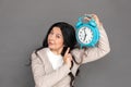 Freestyle. Mature lady standing isolated on grey shwoing time on alarm clock concerned Royalty Free Stock Photo