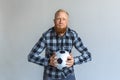 Freestyle. Mature man standing isolated on grey with ball holding breath diligently