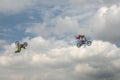Freestyle Motocross trick of two motorcyclists on background of the blue cloud sky. Extreme sport. German-Stuntdays, Zerbst - 2017