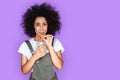 Freestyle. Mulatto girl wearing denim overall standing isolated on blue drinking smiling playful