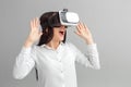 Freestyle. Woman in virtual reality headset standing isolated on gray watching video excited Royalty Free Stock Photo