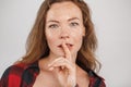 Freestyle. Young woman with freckles standing isolated on grey touching lips showing silence gesture sensual close-up