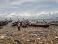 Freetown, Sierra Leone - July 5th 2019: fishing boats on the African coastline with plastic waste on the beach sand. Fishing and