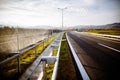 Freeway on a sunny day trough scenic green meadows.Motorway traveling long distance.Asphalt highways road