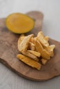 Freeze-dried mango with fresh one on olive wood board Royalty Free Stock Photo