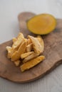 Freeze-dried mango with fresh one on olive wood board Royalty Free Stock Photo