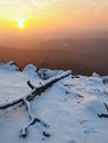 Freeze fallen trunk covered with fresh powder snow, stony rock peak increased from foggy valley. Winter misty sunrise in rocks. Royalty Free Stock Photo