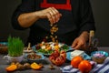 Freezer food prepare in process vegetarian salad with fruits and greens by chef hand in home kitchen. Dark black background. menu