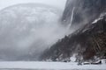 freezing fiord with view of towering waterfall, surrounded by mist