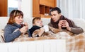 Freezing parents and teenage son warming near warm calorifer Royalty Free Stock Photo