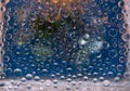 Freezing raindrops are located against the background of a window glass with green, cyan and gold highlights reflected in it. Royalty Free Stock Photo