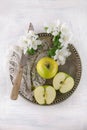 Freh ripe green apple decorated with beautiful apple blossom on white wooden table