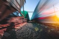 Freight and passenger trains on tracks with motion blur effect at sunset. Railway station