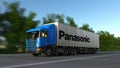 Freight semi truck with Panasonic Corporation logo driving along forest road, seamless loop. Editorial 4K clip