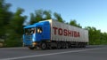 Freight semi truck with Toshiba Corporation logo driving along forest road. Editorial 3D rendering