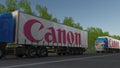 Freight semi trucks with Canon Inc. logo driving along forest road. Editorial 3D rendering