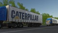 Freight semi trucks with Caterpillar Inc. logo driving along forest road. Editorial 3D rendering