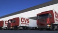 Freight semi trucks with CVS Health logo loading or unloading at warehouse dock. Editorial 3D rendering