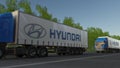 Freight semi trucks with Hyundai Motor Company logo driving along forest road. Editorial 3D rendering