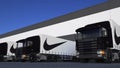 Freight semi trucks with Nike inscription and logo loading or unloading at warehouse dock. Editorial 3D rendering