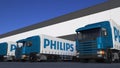 Freight semi trucks with Philips logo loading or unloading at warehouse dock. Editorial 3D rendering