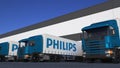 Freight semi trucks with Philips logo loading or unloading at warehouse dock, seamless loop. Editorial animation