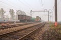 Freight terminal of railway trains. Railway tracks, cars and locomotive in fog. Royalty Free Stock Photo