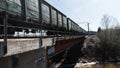 A freight train carrying coal. Clip. A cargo train passing fast on a small bridge above the dirty river, concept of Royalty Free Stock Photo