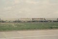 Freight train with graffiti passing through rural landscape on overcast day Royalty Free Stock Photo