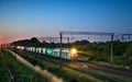 Freight train with lights on while moving in the evening