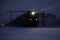 Freight train at night. The headlights and locomotive headlights illuminate the falling snow. Russia Royalty Free Stock Photo