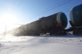 Freight train with oil tanks in motion. Snow dust flies from a passing train at high speed. Frosty sunny day. Winter. Russia Royalty Free Stock Photo