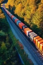 A freight train passing through a dense forest, surrounded by vibrant autumn foliage Royalty Free Stock Photo