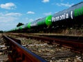 Green freight train of ethanol tanker cars under blue sky