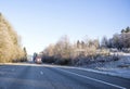 Big rigs semi trucks convoy with commercial cargo on flat bed semi trailers running on wide highway with winter frosty grass and