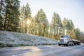 White big rig day cab semi truck for local haul transporting cargo on flat bed semi trailer running on winter road with frost Royalty Free Stock Photo