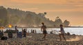 Beautiful young people playing volleyball on beach at the summer sunset