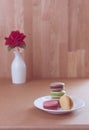 Frence sweet delicacy macaroons and red rose vase on grune wood table background Royalty Free Stock Photo