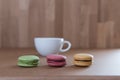 Frence sweet delicacy macaroons and white coffee cup on grunge wood background Royalty Free Stock Photo