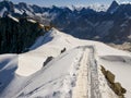 French Alps mountains snowy ridge view with silhouettes of climbers as roping team descending on the snowy slope under Aiguille du