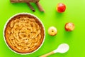 French apple tart aside Gala apples, cooking spoon and cinnamon sticks on a green background. Flat lay. Top view