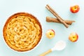 French apple tart aside Gala apples, cooking spoon and cinnamon sticks on a light blue background. Flat lay. Top view