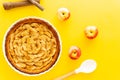 French apple tart aside Gala apples, cooking spoon and cinnamon sticks on a yellow background. Flat lay. Top view