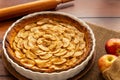 French apple tart aside Gala apples in a jute or burlap bag and a rolling pin on a vintage wood table