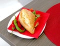 The French baguette on a porcelain saucer with a red napkin is lined with red and green peppers Royalty Free Stock Photo